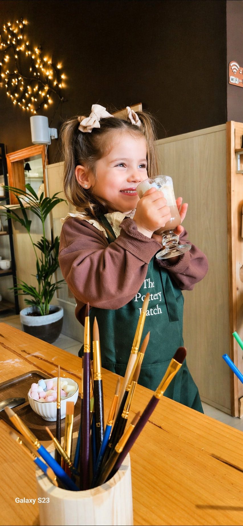 Young guest enjoying a hot chocolate in her apron