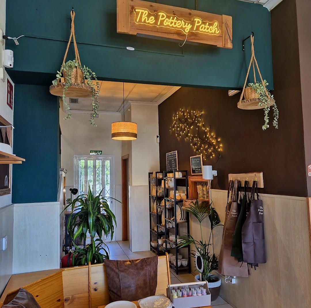 Inside The Pottery Patch — neon sign, aprons and pottery shelves