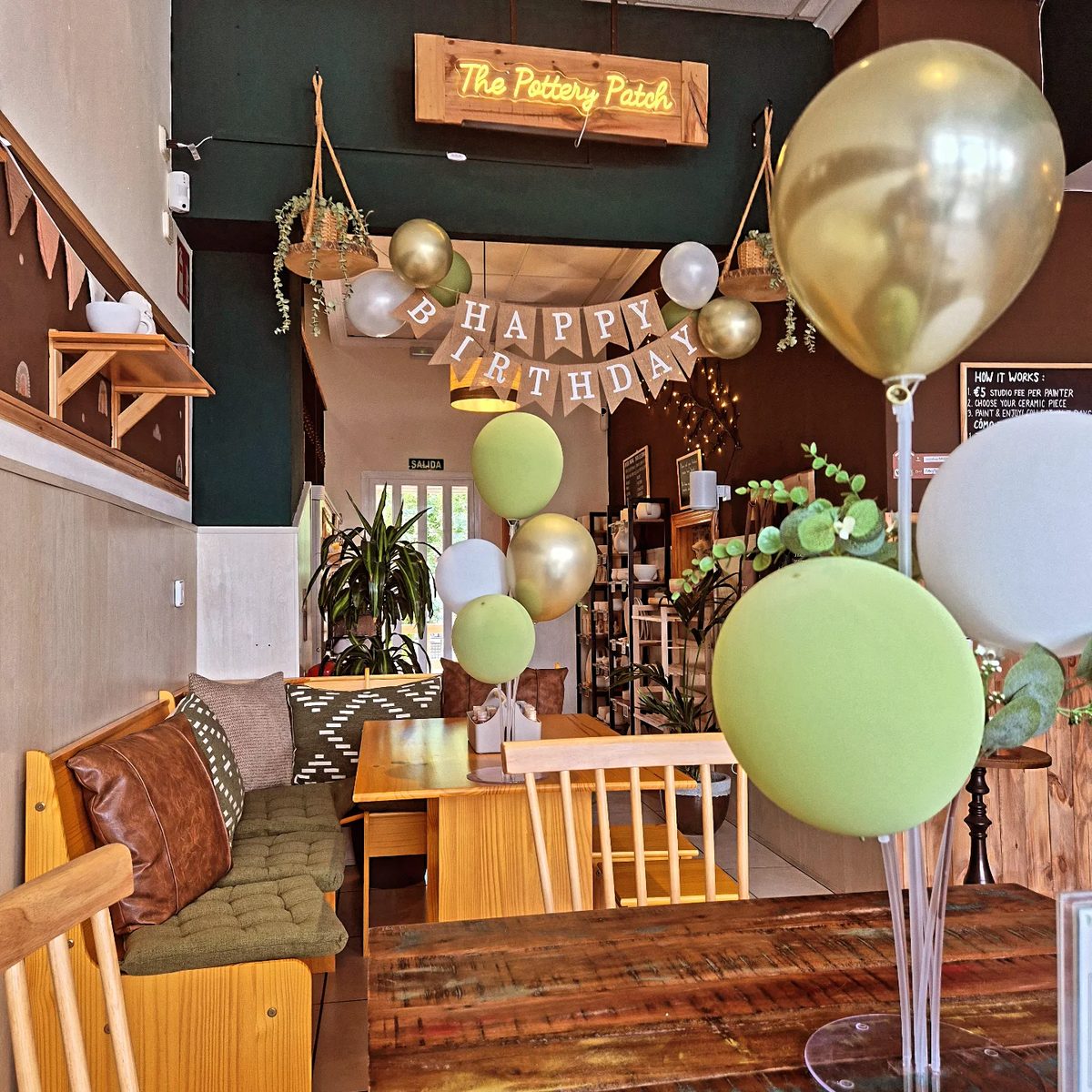 Birthday party set up with balloons under The Pottery Patch neon sign
