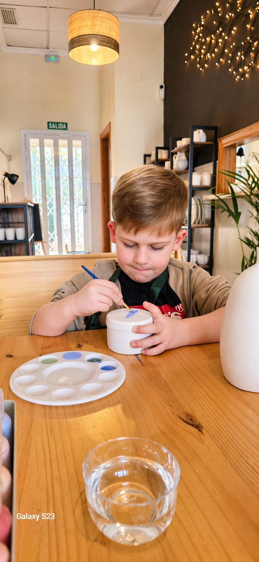 A child painting their own pottery piece